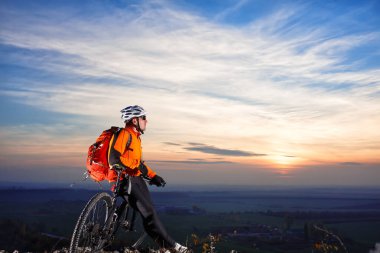 Bisikletçi bir tepe üstünde sırt çantası ile