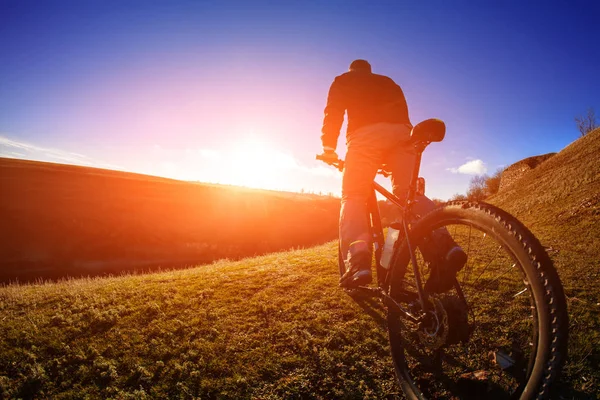 Cyklisten stå med mountainbike i solnedgången — Stockfoto