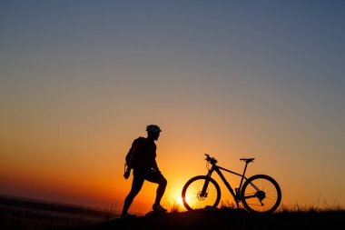 Siluet adam stand çayır üzerinde dağ bisikleti ile