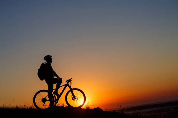 Siluett man stå med mountainbike på ängen — Stockfoto