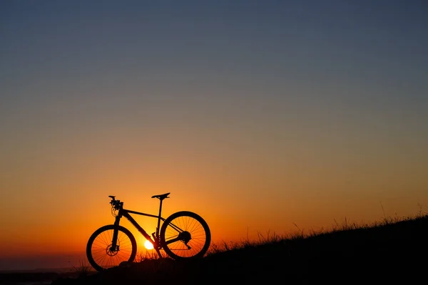 Silhouette of a bike on the hills at sunset. — Stock Photo, Image