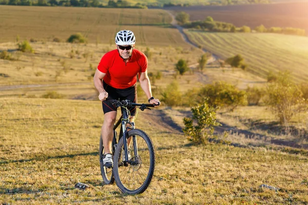 Ciclista turista de viaje en bicicleta de montaña. Paisaje de otoño. Deportista en bicicleta en jersey rojo y casco blanco — Foto de Stock