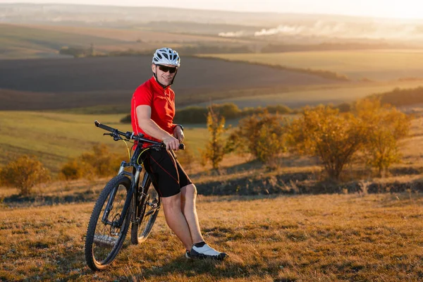 Dağ bisikleti motorcu turizm seyahat. Sonbahar manzara. Kırmızı forma ve beyaz kask bisikletle sporcu