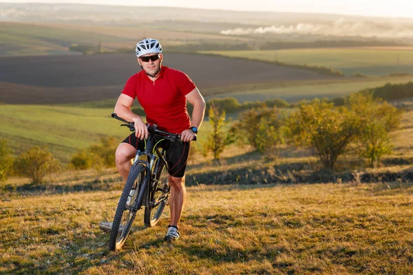 Ciclista turista de viaje en bicicleta de montaña. Paisaje de otoño. Deportista en bicicleta en jersey rojo y casco blanco — Foto de Stock