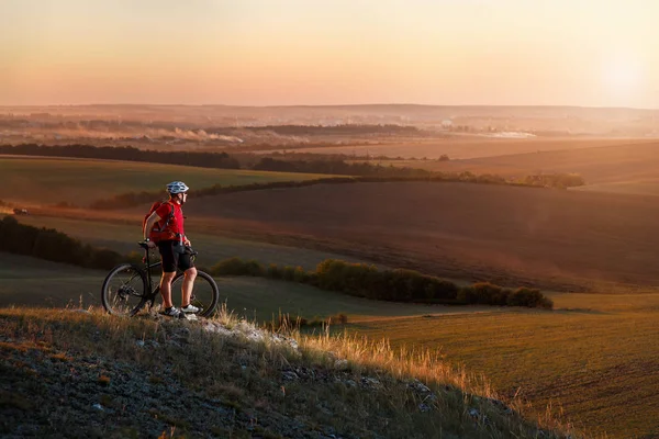 Biker tourist travel on mountain bike. Autumn landscape. Sportsman on bicycle in red jersey and white helmet — Stock Photo, Image