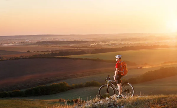 Biker podróży turystycznych na rowerze górskim. Jesienny krajobraz. Sportowca na rowerze w czerwonej koszulce i biały kask — Zdjęcie stockowe