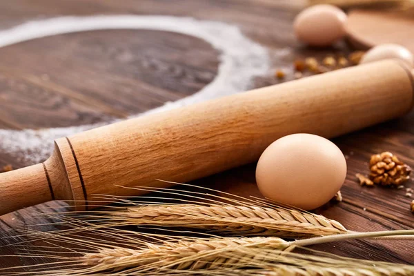 Arriba ver huevos, masa, harina y rodillo en la mesa de madera —  Fotos de Stock