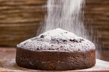 Tahta arka planda beyaz tabakta nefis çikolatalı pasta.