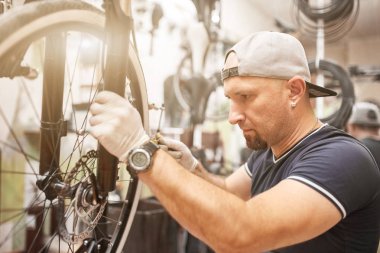 Mechanic repairing a mountain bike in a workshop clipart