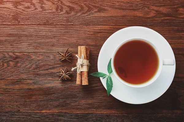 Beyaz porselen fincan çay tarçın, limon, nane yaprakları ve çay süzgeci