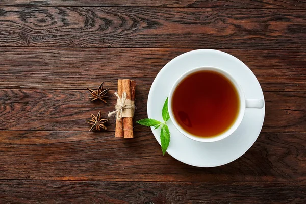 Beyaz porselen fincan çay tarçın, limon, nane yaprakları ve çay süzgeci