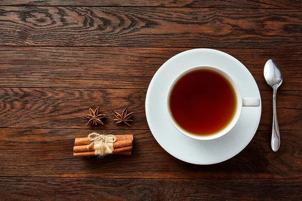 Taza de té de porcelana blanca con palitos de canela, limón, hojas de menta y colador de té — Foto de Stock