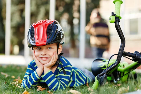 헬멧 블루 균형 실행 자전거 자전거와 함께 잔디에 앉아 있는 소년. 건강 한 취학 전 아동 여름 활동. — 스톡 사진