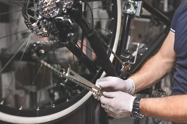 Mecânico de bicicletas em uma oficina no processo de reparação — Fotografia de Stock