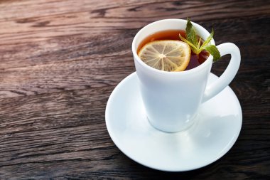 Beyaz fincan limonlu çay, tarçın sopa, ahşap masa üzerinde yün atkı örme