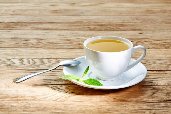 Чай с лимоном в белой чашке, коричные палочки, вязаный шерстяной шарф на деревянном столе — стоковое фото