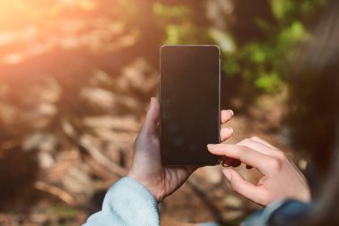 Yağmur ormanı bahçede boş ekran cep telefonu tutan kız el