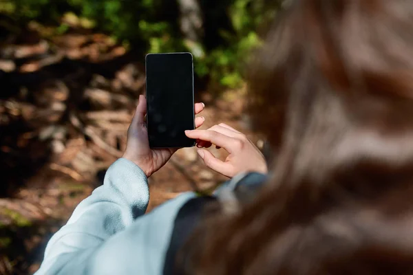 Chica de mano celebración de pantalla en blanco teléfono móvil en el jardín de la selva tropical — Foto de Stock
