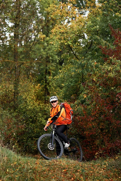Candid tiro al aire libre de joven jinete concentrado en equipo de protección sentado en su bicicleta — Foto de Stock