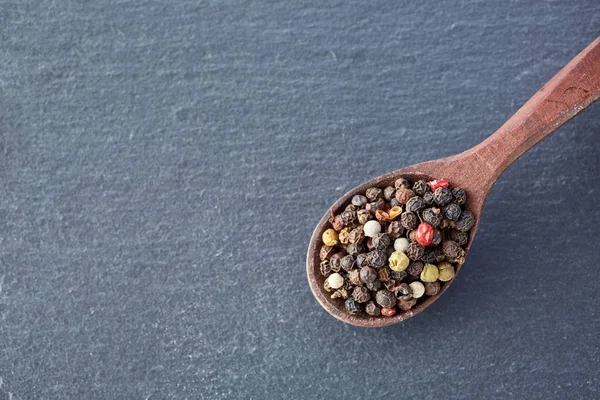 Čínský pepř, Sichuan pepř v vařečku na černé břidlicové kamenné desky — Stock fotografie