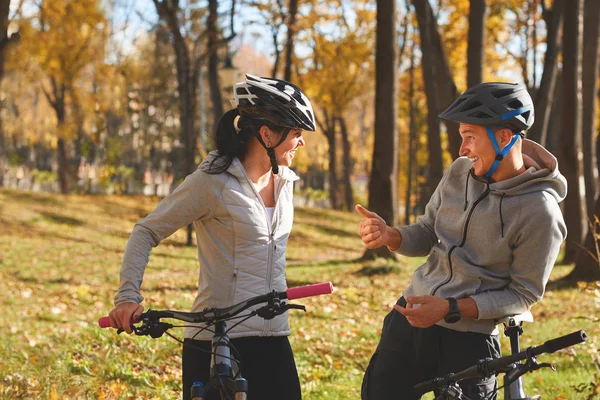 Felice giovane coppia divertirsi in bicicletta nella soleggiata giornata autunnale nel parco . — Foto Stock