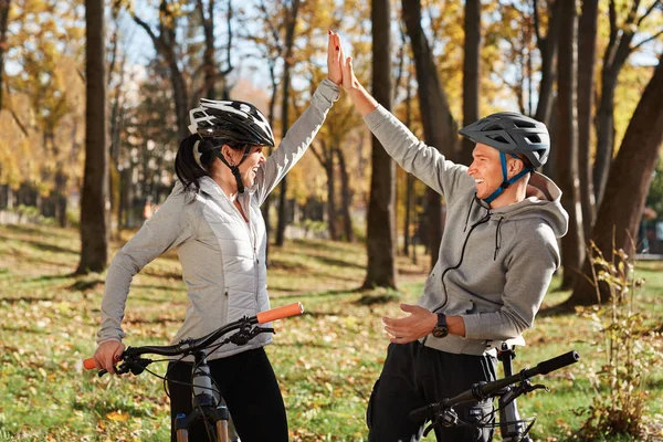 Felice giovane coppia divertirsi in bicicletta nella soleggiata giornata autunnale nel parco . — Foto Stock
