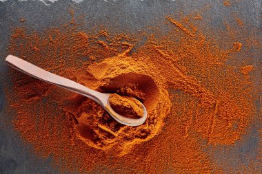 Doku arka plan. Kırmızı biber biber toz tahta kaşıkla karıştırılarak. Üstten Görünüm