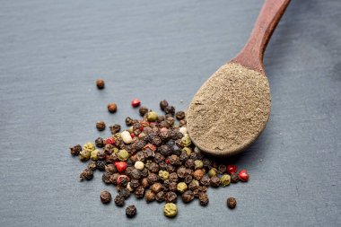 Closeup karabiber tüm siyah taş masada tahta kaşık