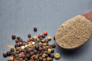 Closeup karabiber tüm siyah taş masada tahta kaşık