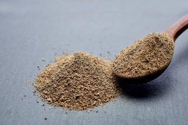 Closeup karabiber tüm siyah taş masada tahta kaşık