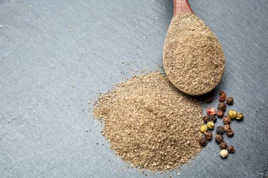 Closeup karabiber tüm siyah taş masada tahta kaşık