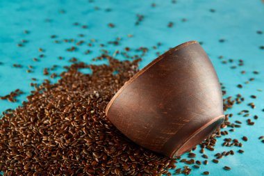 Keten tohumu bir kil kase üzerinde izole mavi arka plan, yakın çekim, sığ derinlik-in tarla