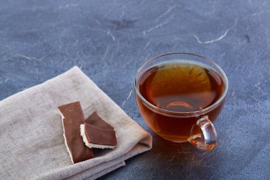 Bir cam bardak koyu grimsi mermer zemin üzerine çikolata parçaları ile siyah çay. Kahvaltı arka plan