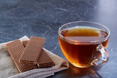 Siyah çay waffle koyu grimsi mermer zemin ile cam fincan. Kahvaltı arka plan