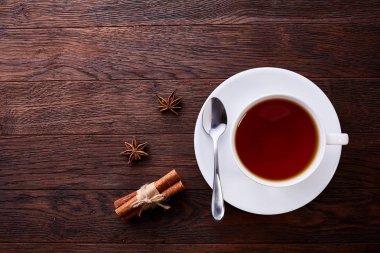 Siyah çay ve fincan tabağı ile tarçın ve anasonu vintage tablo arka plan üzerinde beyaz porselen Çin fincan. Üstten Görünüm.