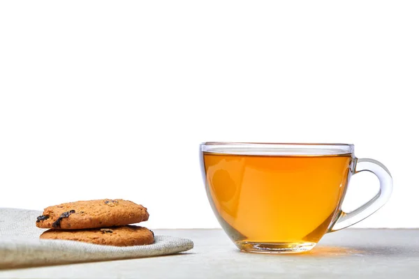 Cerrar imagen de té en taza transparente con galletas sobre una servilleta de algodón aislada sobre fondo blanco — Foto de Stock