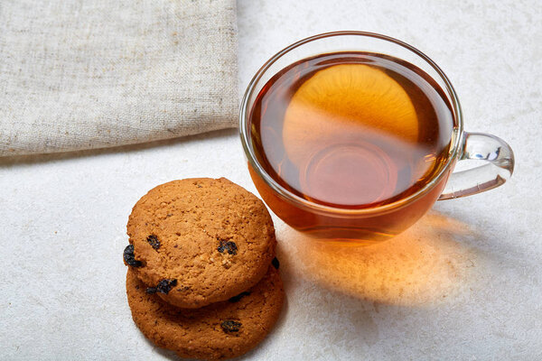 Top view close up picture of tea in transparent cup with biscuit cookies on a cotton napkin isolated on white background