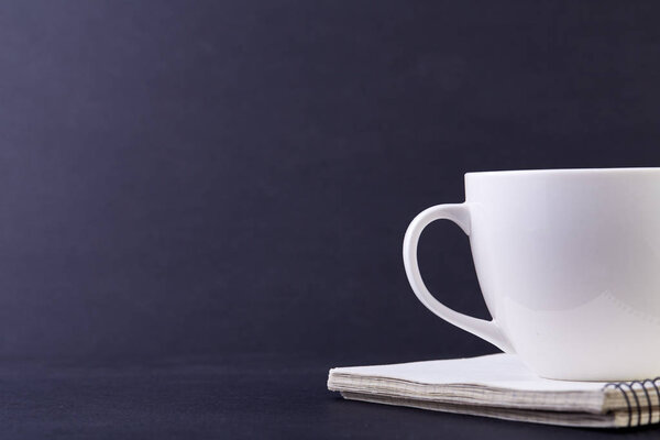 Взгляд сбоку крупным планом на пол чайной чашки и блюдце, изолированные на темно-сером фоне, в помещении, на низкой глубине поля
