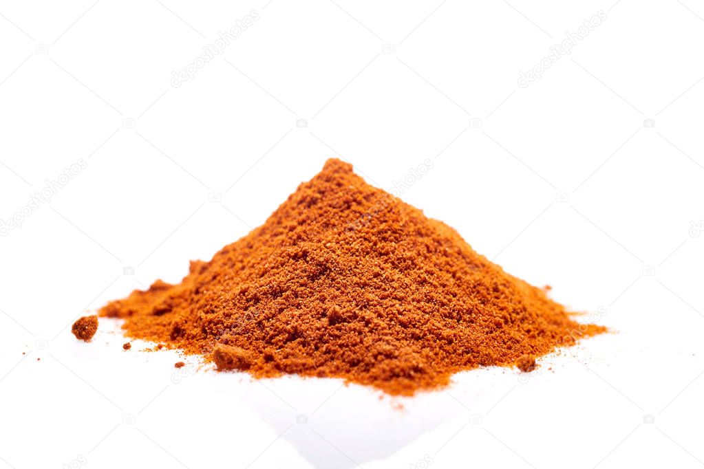 A pile of ground powder paprika isolated on white background, close-up, shallow depth of field