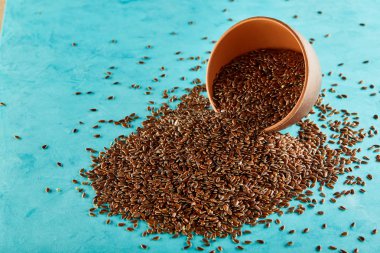 Keten tohumu bir kil kase üzerinde izole mavi arka plan, yakın çekim, seçici odak, dikey.