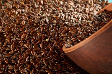 Keten tohumu bir kil kase üzerinde izole mavi arka plan, yakın çekim, seçici odak, dikey.