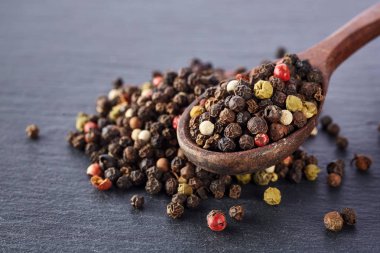 Siyah gıda arka plan baharatlar ile. Biber bir şeyl taş üzerinde bir tahta kaşıkla karışımı.