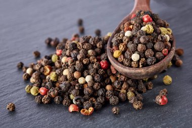 Siyah gıda arka plan baharatlar ile. Biber bir şeyl taş üzerinde bir tahta kaşıkla karışımı.