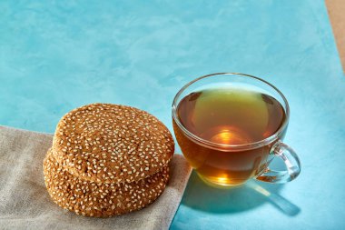 Cam bardak çay ve yulaf ezmesi çikolata kurabiye yakın çekim mavi zemin üzerine.