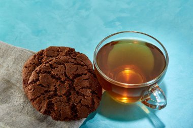 Cam bardak çay ve çikolata Çerezler yakın çekim mavi zemin üzerine.