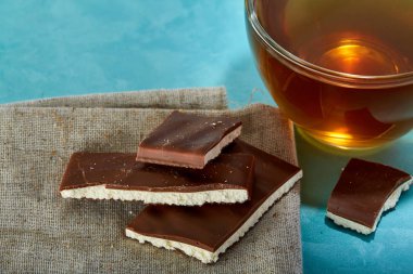 Mavi arka plan çay ve çikolata yakın çekim cam fincan.