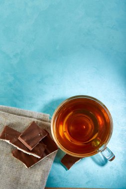 Mavi arka plan çay ve çikolata yakın çekim cam fincan.