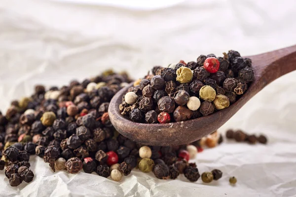 Pois poivrés noirs sur une cuillère en bois — Photo