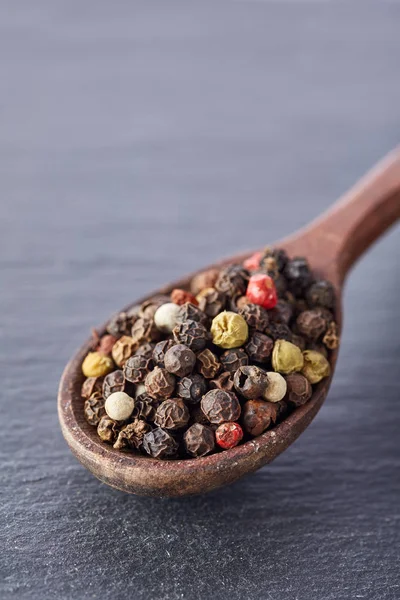 Pimienta china, pimienta de Sichuan en cuchara de madera en plato de piedra de pizarra negra — Foto de Stock