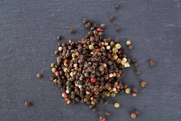 Granel de varios granos de pimienta semillas se mezclan en piedra oscura —  Fotos de Stock